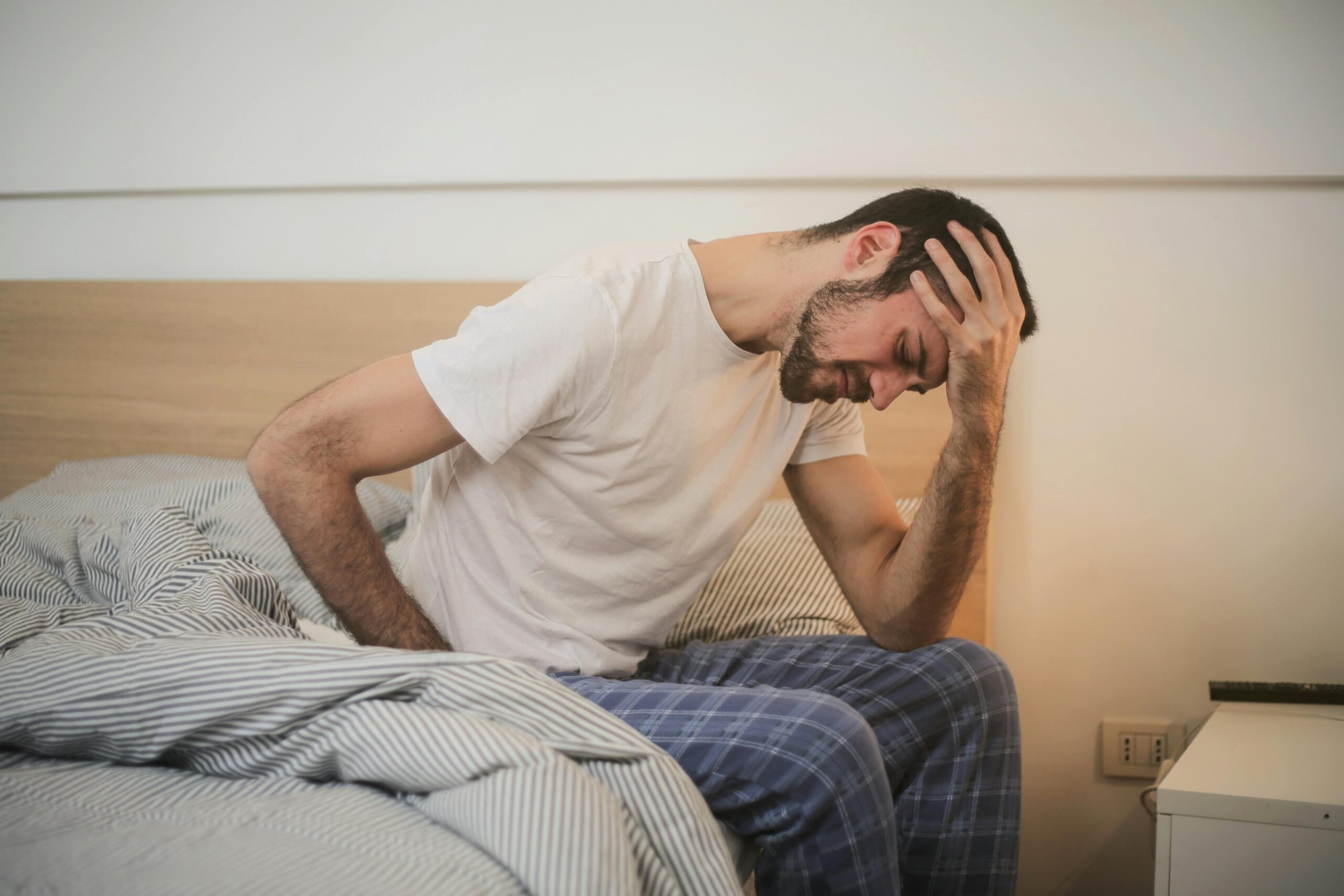 uomo seduto sul letto con dolori schiena